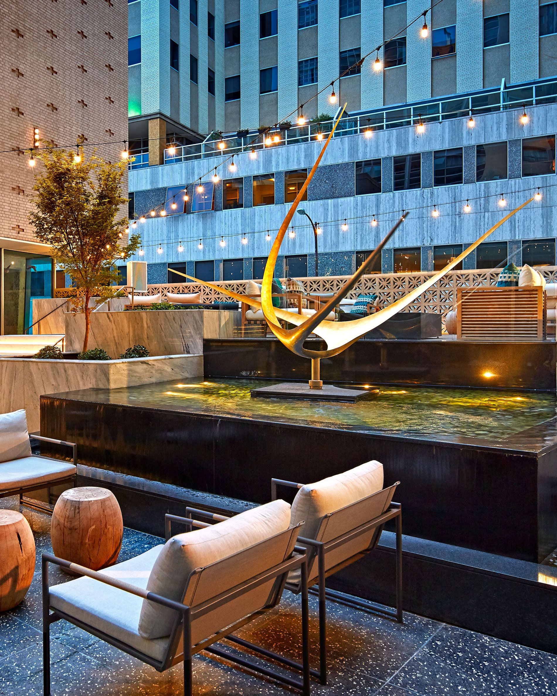 The restored Wishing Star sculpture lit at dusk as the centerpiece of a water feature on The Statler's terrace